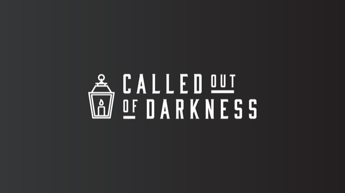 The Called Out of Darkness lantern logo reversed on charcoal
